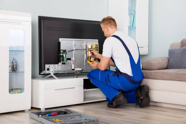 young male electrician in overall checking television